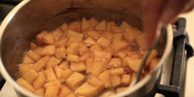 Apple chunks cooking in a pot with cinnamon for an apple compote