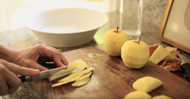 Slicing apples into paper thin slices on a cutting board 