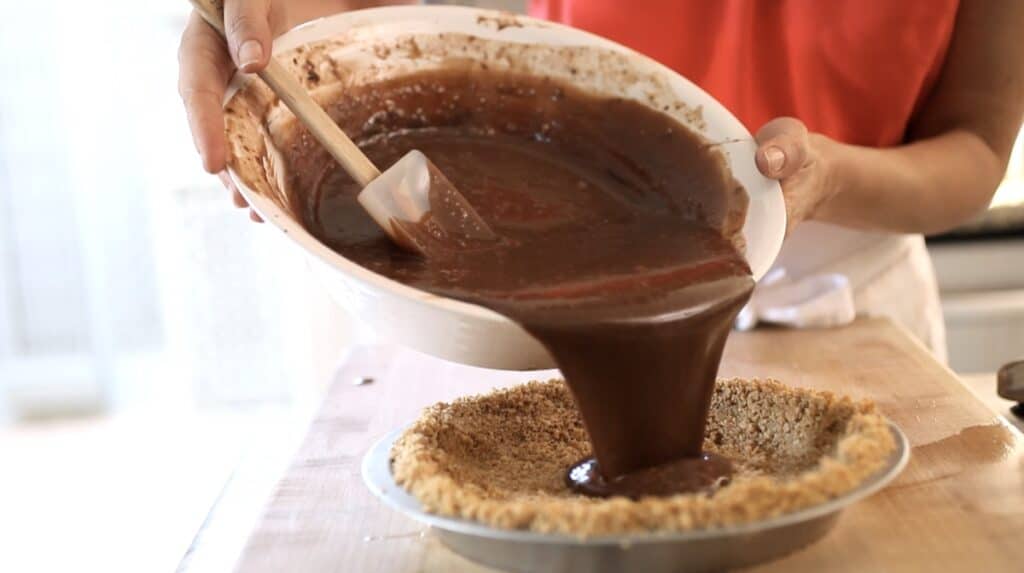 pouring chocolate mixture into graham cracker pie crust