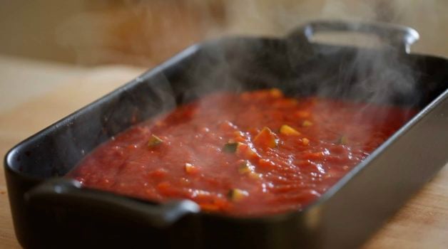 a casserole filled with tomato sauce with steam rising