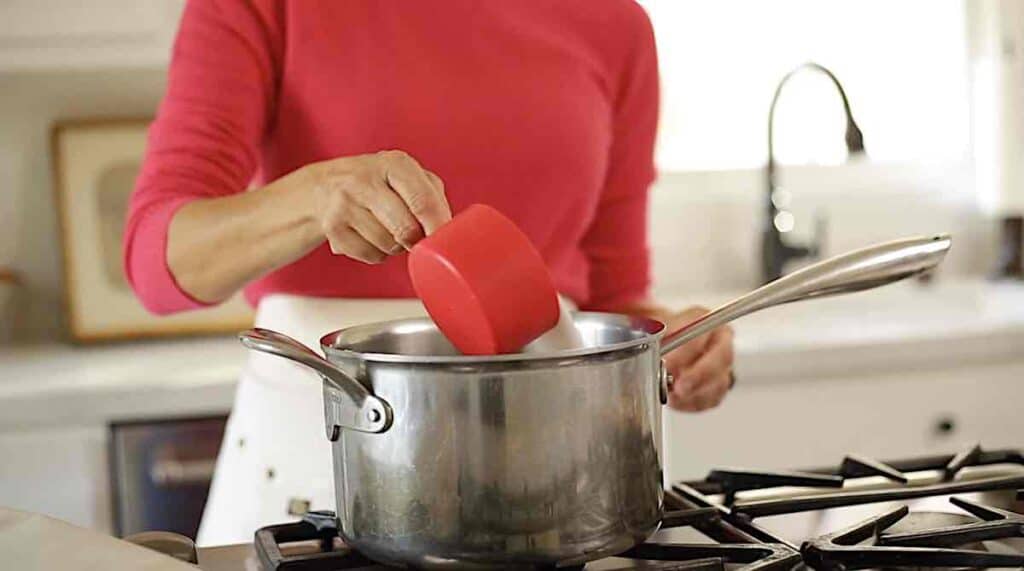 adding white sugar to a large sauce pot