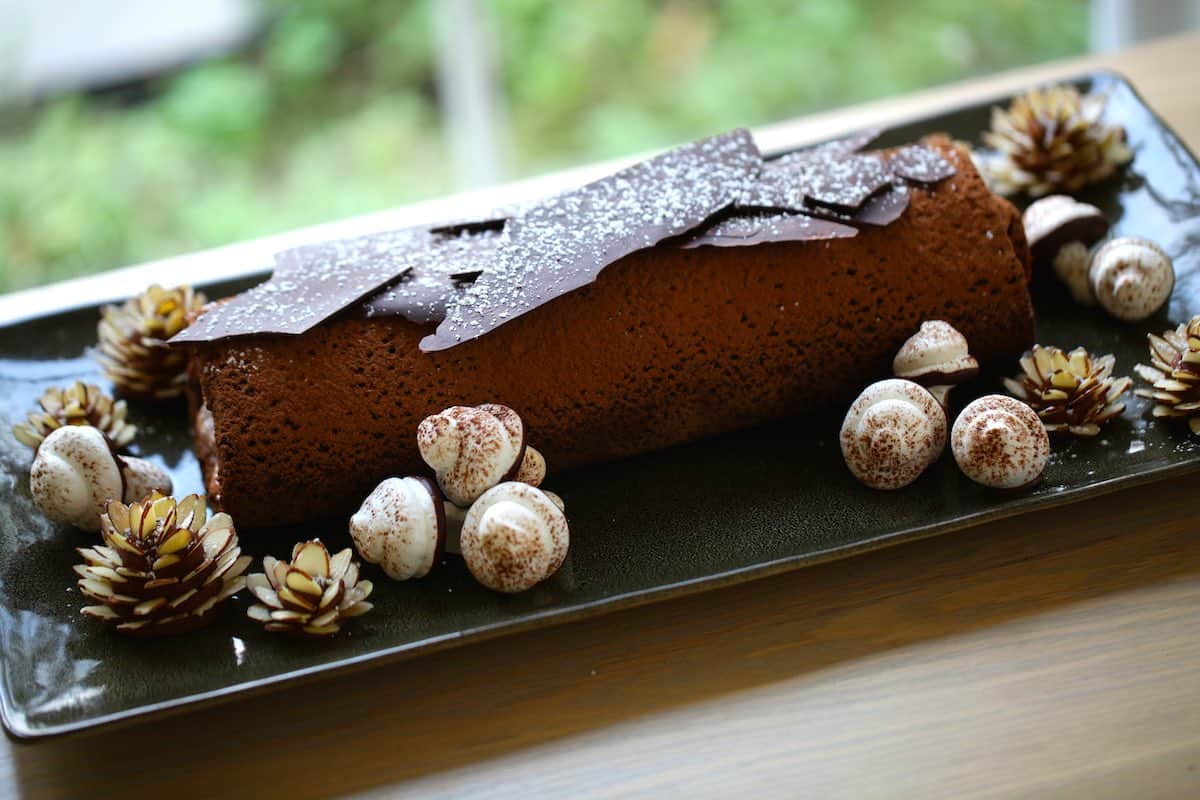 a buche de noel with decorations on a long green platter