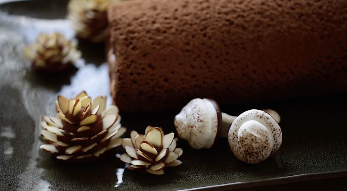 the corner of a buche de noel with meringue mushrooms and fondant pinecones