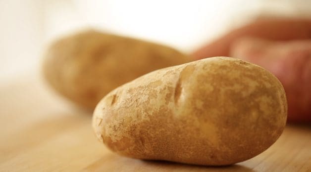 Russet potatoes on a wooden cutting board