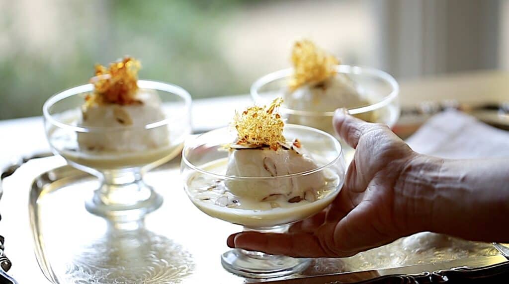 a person placing a bowl of Ile Flottante on a silver tray