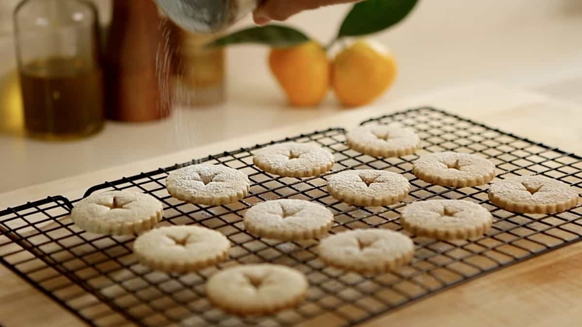 linzer cookie tops being dusted with powdered sugar