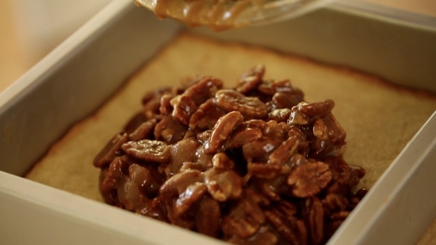 pouring pecan filling into shortbread crust