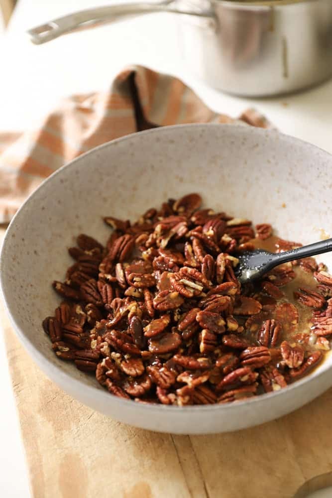 Pecans in a bowl with brown sugar syrup.
