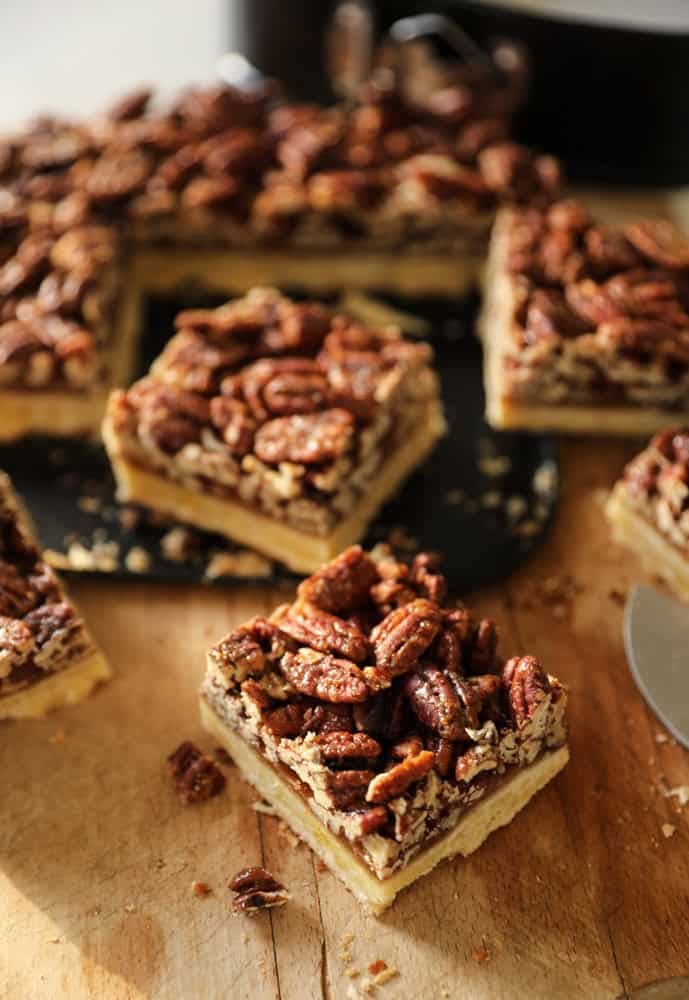 Pecan bars cut into squares on a cutting board.