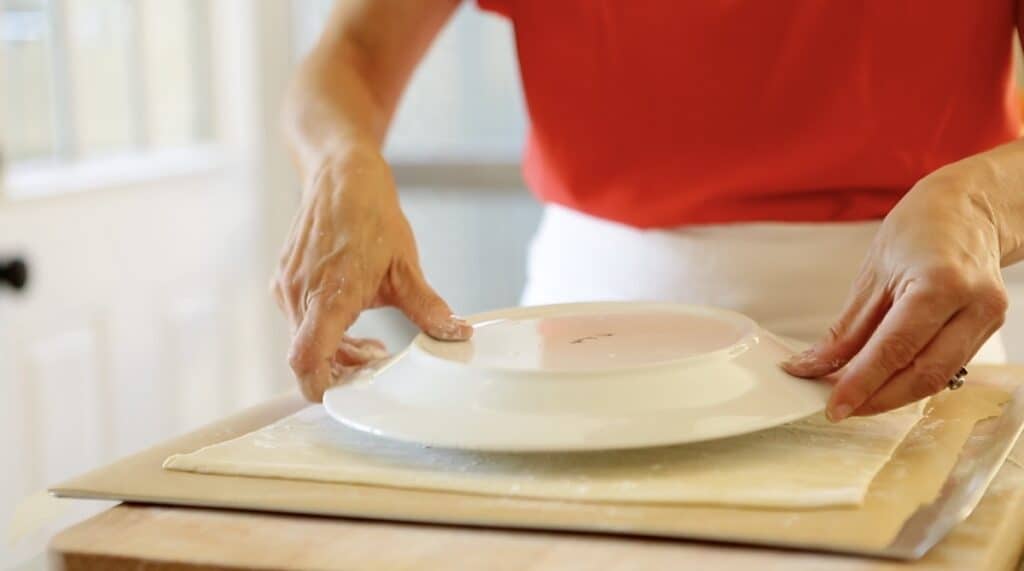 placing a dinner plate on a puff pastry round