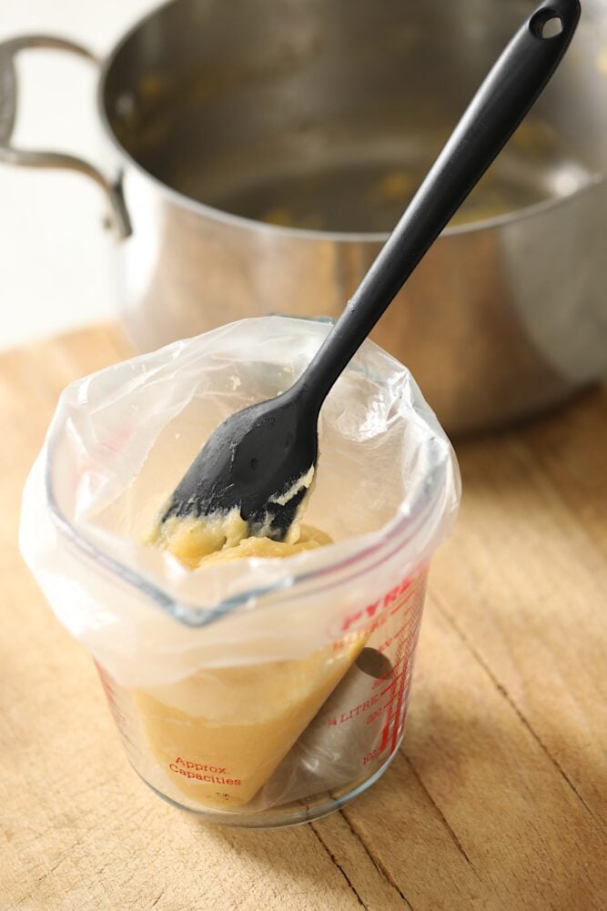 Piping bag in pyrex pitcher filled with pate a choux pastry dough.