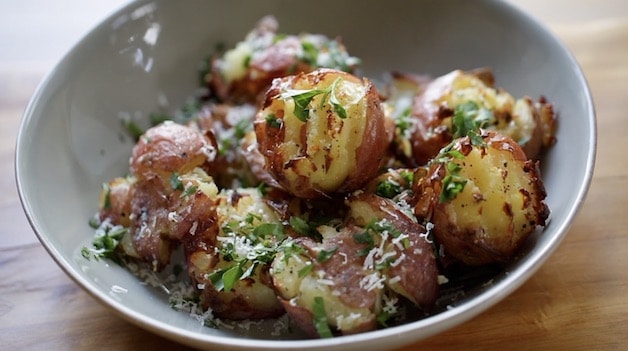Bowl of smashed potatoes with parsley and parmesan cheese
