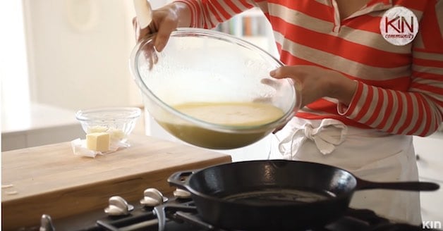 Egg batter being poured into a cast-iron skillet on a stovetop