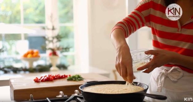 Adding cheese to an easy frittata recipe setting in a skillet on the cooktop