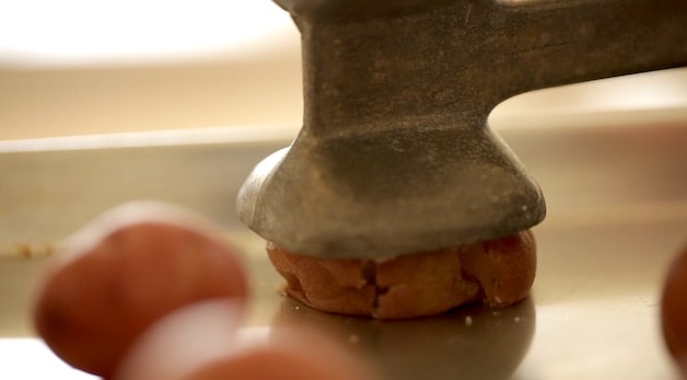 smashing a cooked potato with a meat mallet