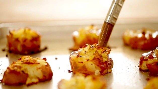 Brushing garlic butter on a smashed potato