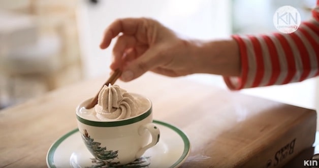 Adding cinnamon stick to a cup of hot chocolate in a christmas cup