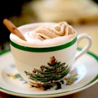 Gingerbread hot chocolate with whipped cream in Christmas themed cup and saucer