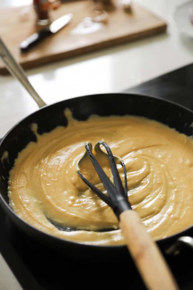 Cheese sauce being made in a non-stick skillet.