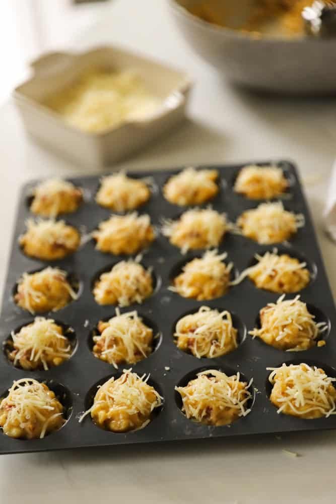 Mini muffin mold filled with macaroni and cheese sauce.