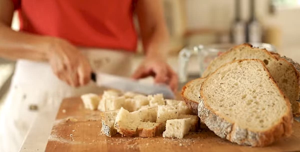 bread being cut into cubes with a chef's knife