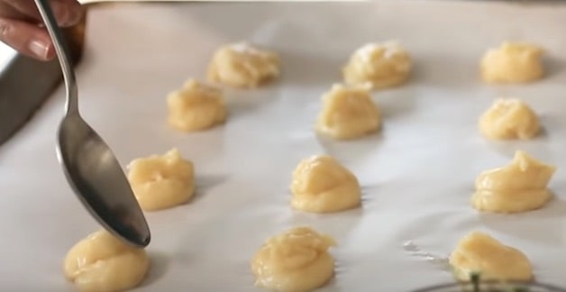 Tapping choux pastry down with wet spoon