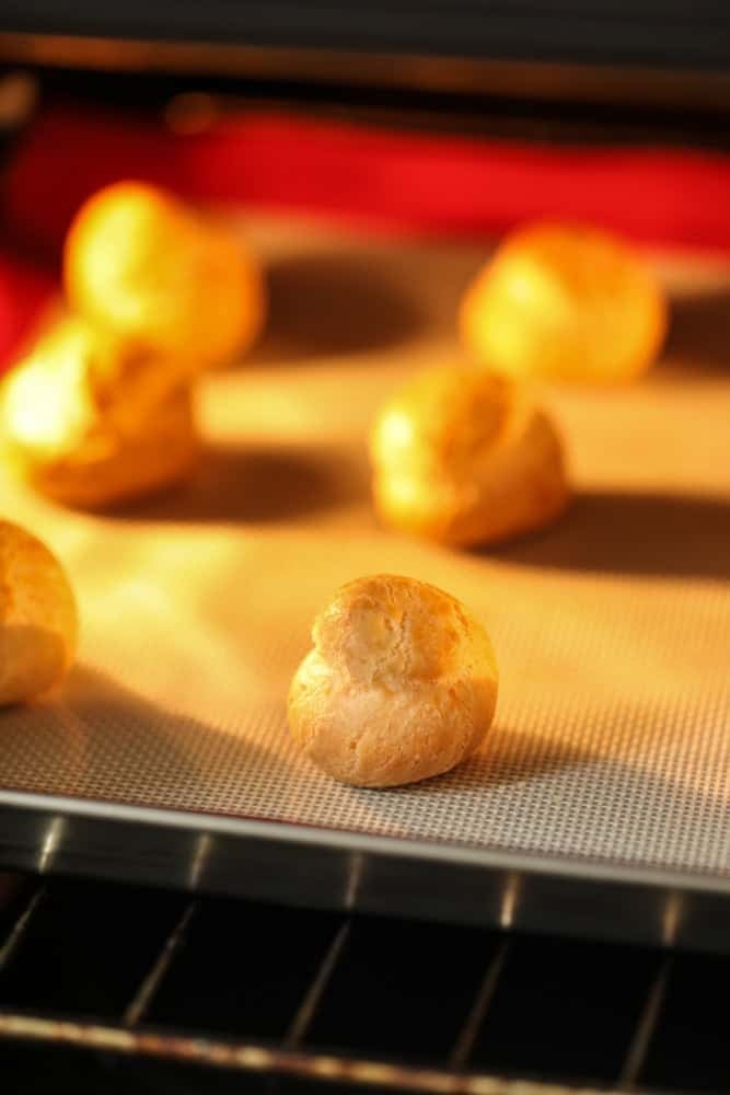 choux pastry shells risen and baking in the oven.