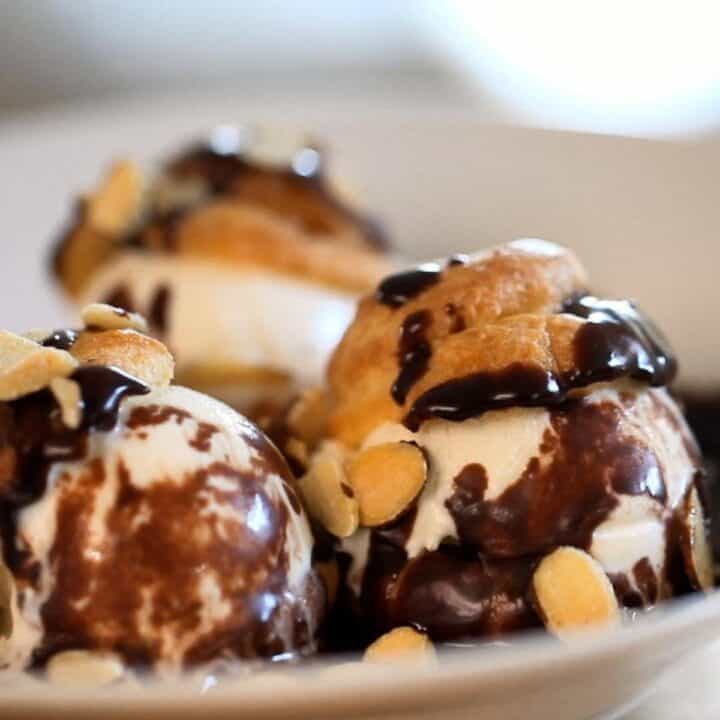 Profiteroles with Chocolate sauce and vanilla ice cream in a white bowl