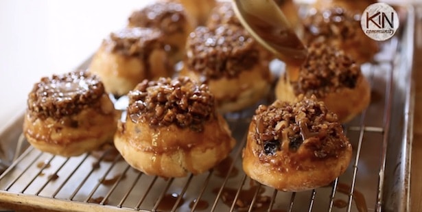 Pouring extra sticky sauce on sticky buns on a rack