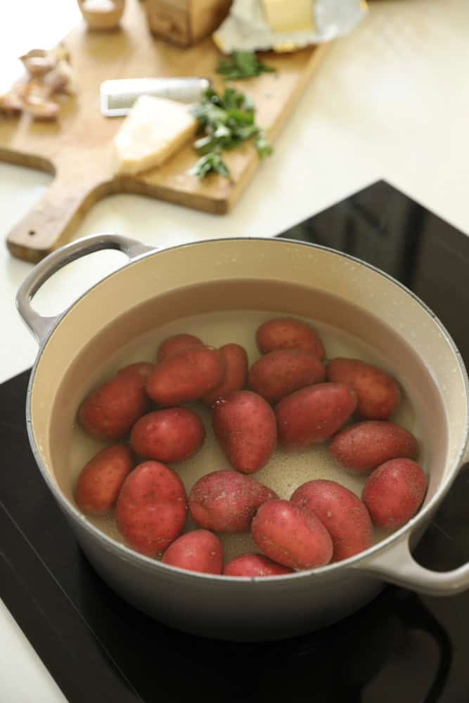 Red potatoes boiling in a big gray pot.