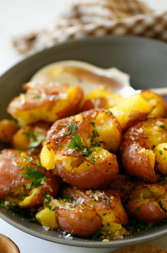 Smashed potatoes in a bowl with fresh parsley, garlic butter and sea salt. 