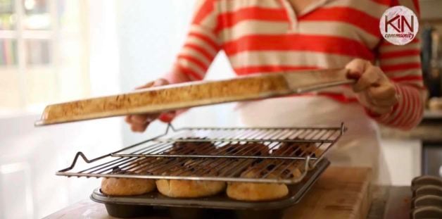 cookie sheet being placed on top of sticky buns before flipping them