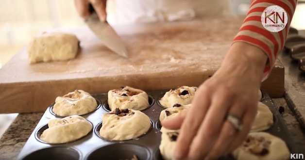 Placing sticky bun dough slices into muffin tin before baking