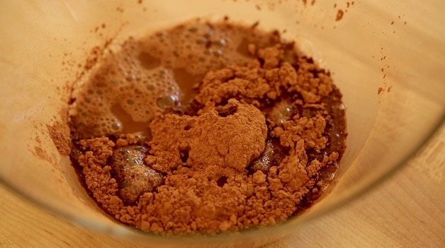 Glass bowl with unsweetened cocoa powder mixed with hot water