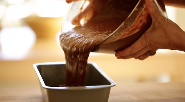 Pouring chocolate banana bread batter into a loaf pan