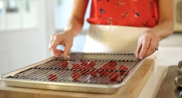 Rimmed Baking sheet with cherrry tomatoes and roasting rack on top 