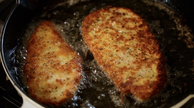 Breaded chicken cutlets frying in oil in a pan