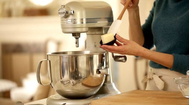 Adding butter from a black dish to a stand mixer beating mashed potatoes