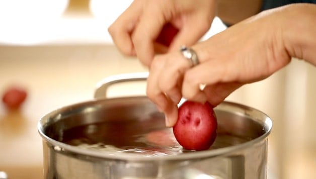 placing red new potatoes in a pot of boiling water