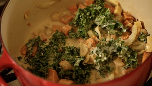 Vegetables and kale in a large pot with coconut milk