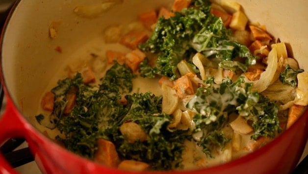 Vegetables and kale in a large pot with coconut milk