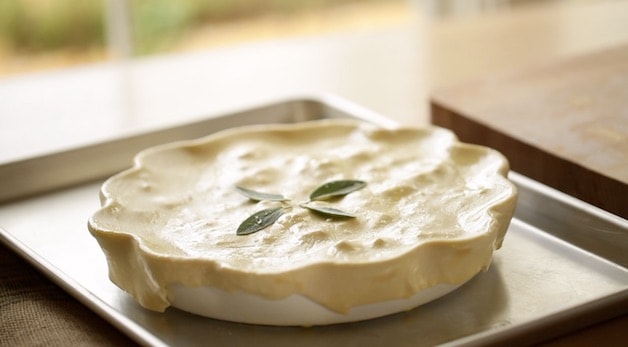 Pot pie covered with the dough with sage leaves on top on baking sheet