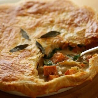 Pot pie with serving cut out of it with silver serving spoon