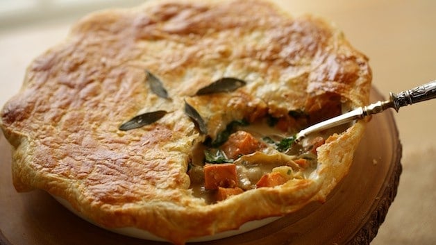 Pot pie with serving cut out of it with silver serving spoon