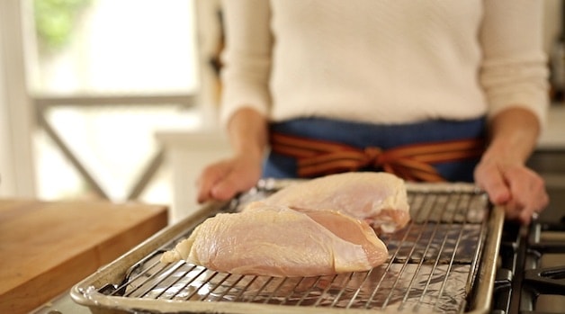 2 chicken breasts on roasting rack going into oven to bake