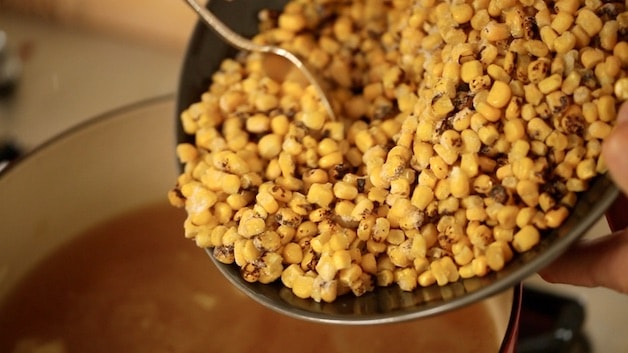 Frozen charred corn being added to a soup pot