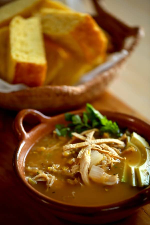 White Chicken Chili with cornbread in the background in a basket