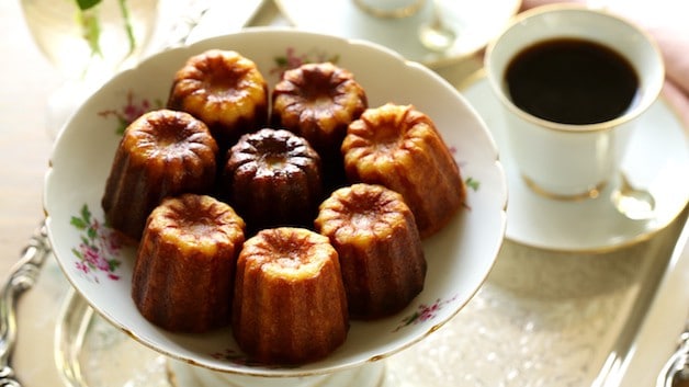 Caneles in a Floral Serving Dish with a cup of coffee in background