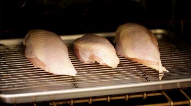 Raw chicken on wire rack in oven for Enchiladas Suizas