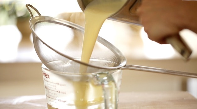 Straining Creme Anglaise through a seive into a heat safe ptcher